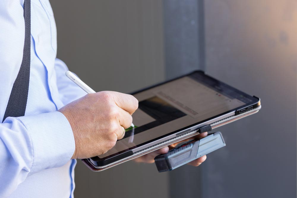 Person in Hemd bedient mit einem Stift ein Tablet